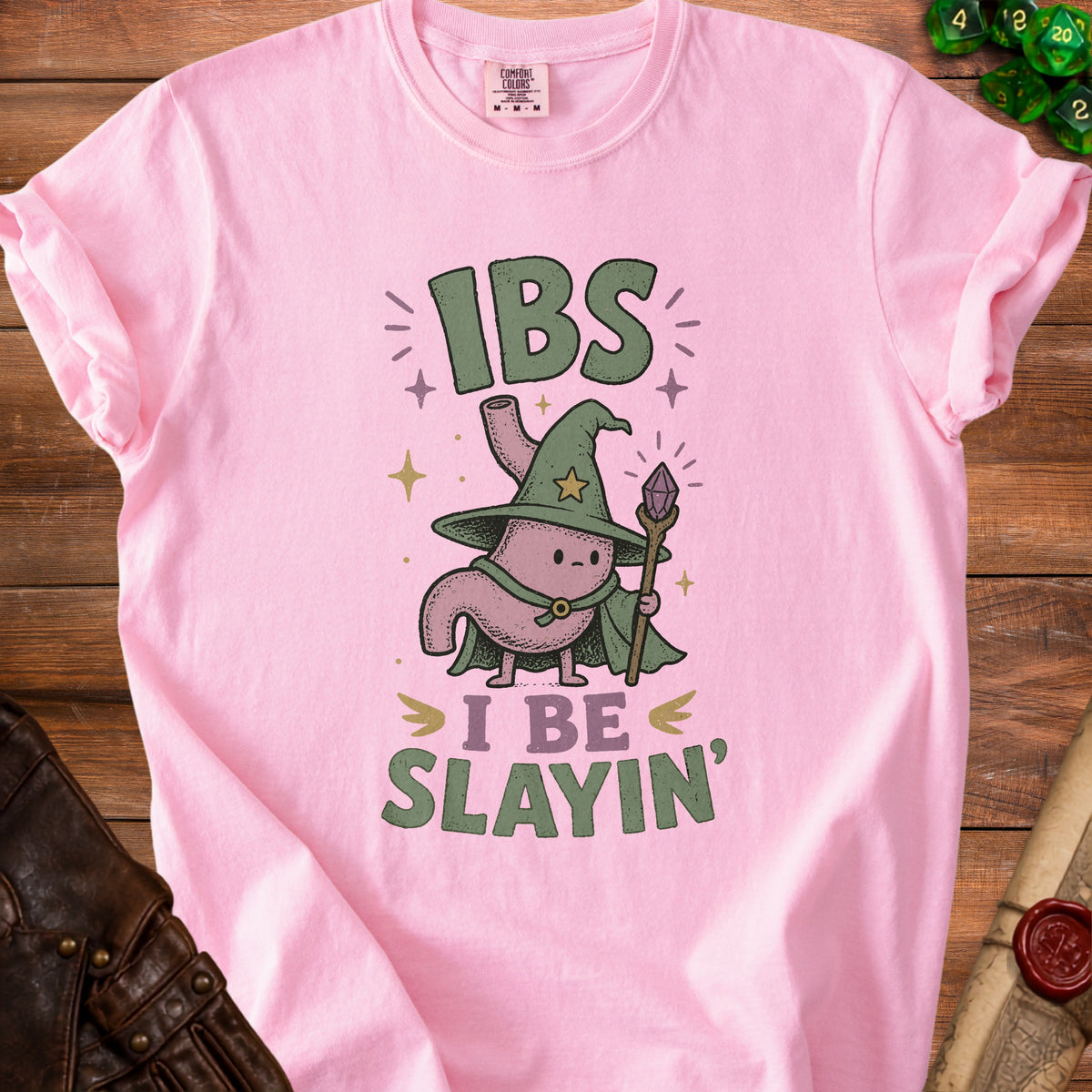 Pink t-shirt with graphic of a stomach wizard saying "IBS I Be Slain".