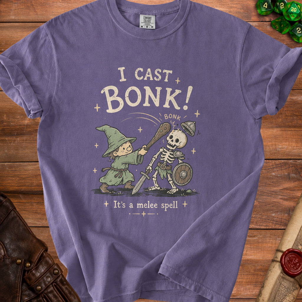 Purple t-shirt graphic of wizard casting "bonk" spell on a skeleton, "I cast bonk!"