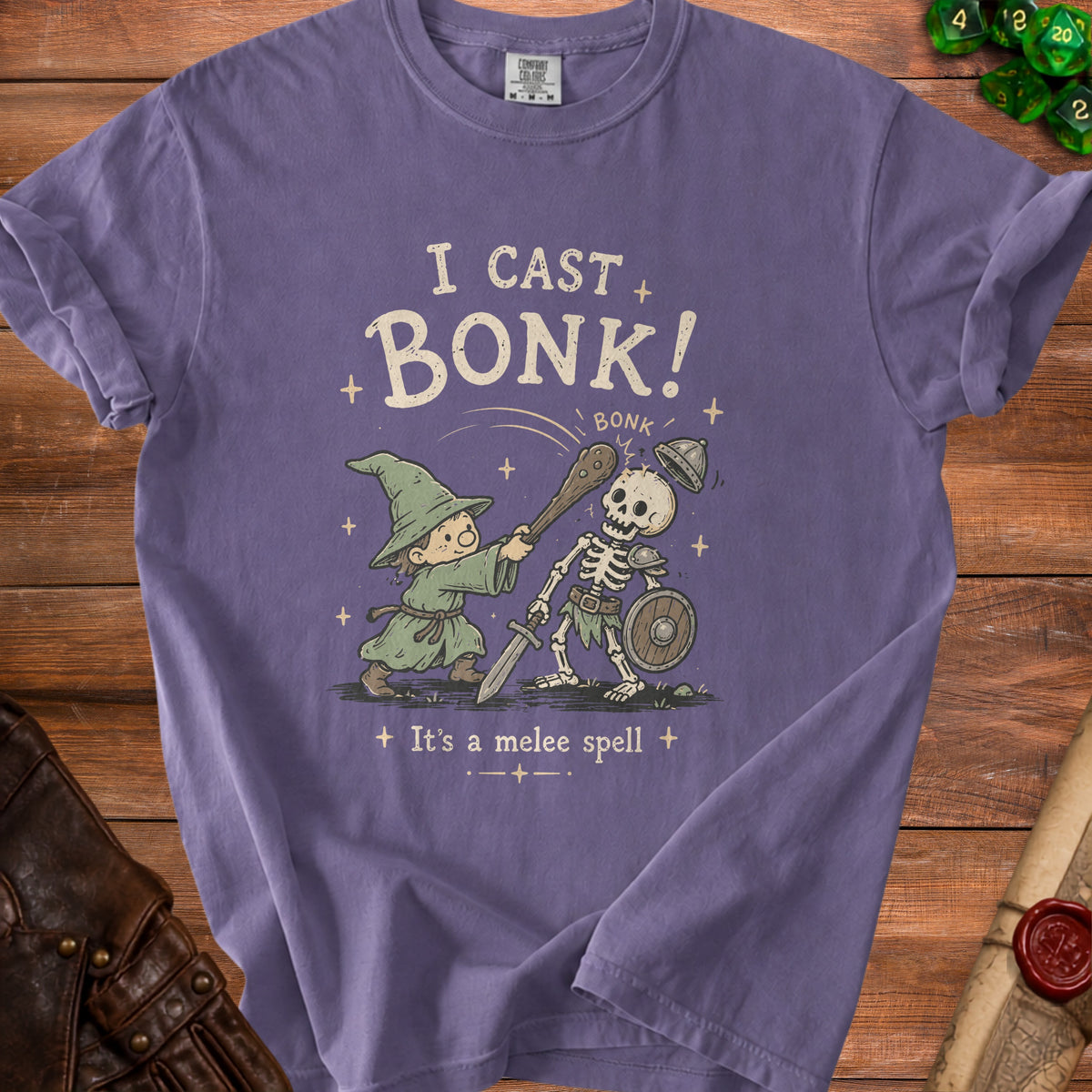 Purple t-shirt graphic of wizard casting "bonk" spell on a skeleton, "I cast bonk!"