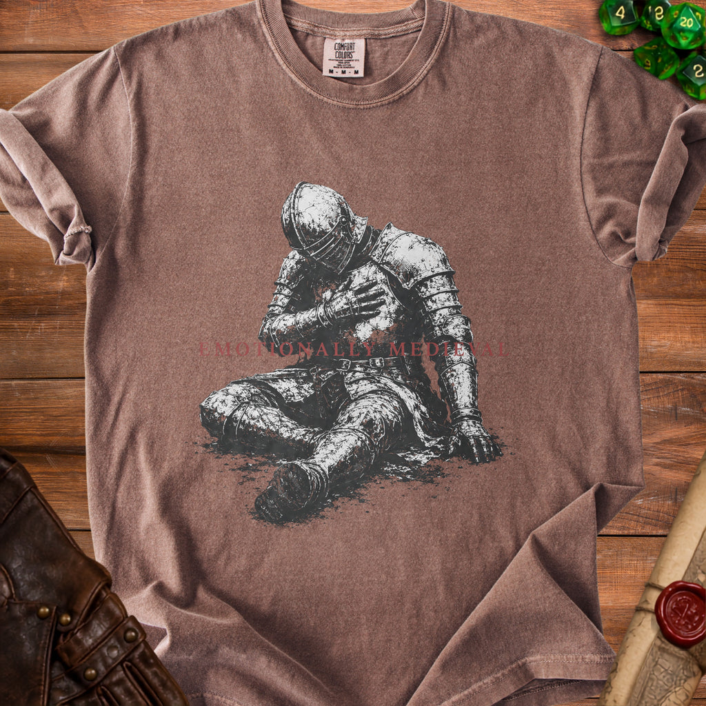 Brown t-shirt with a distressed knight holding hand to chest print and "Emotionally Medi" text.