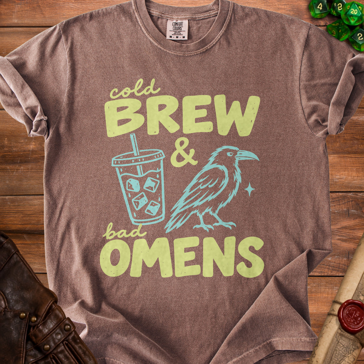 Brown t-shirt with "cold BREW & bad OMENS" graphic featuring an iced coffee and a raven.