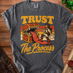Graphic tee with treasure chest monster, adventurer, and text "TRUST The Process".