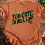 Orange t-shirt with green text "TOO CUTE TO ROLL LOW" and dice graphic.
