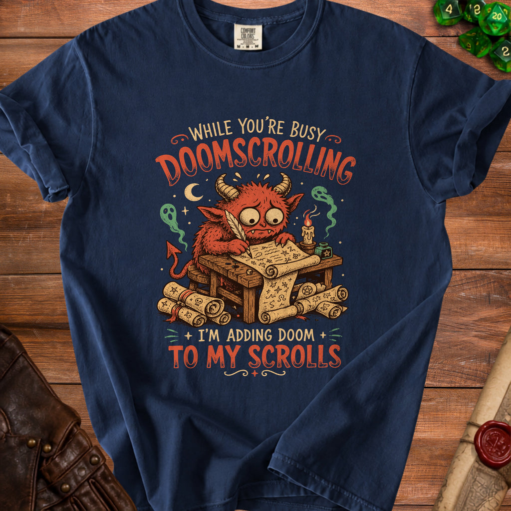 Navy blue shirt with illustration of a monster doomscrolling and adding doom to scrolls.