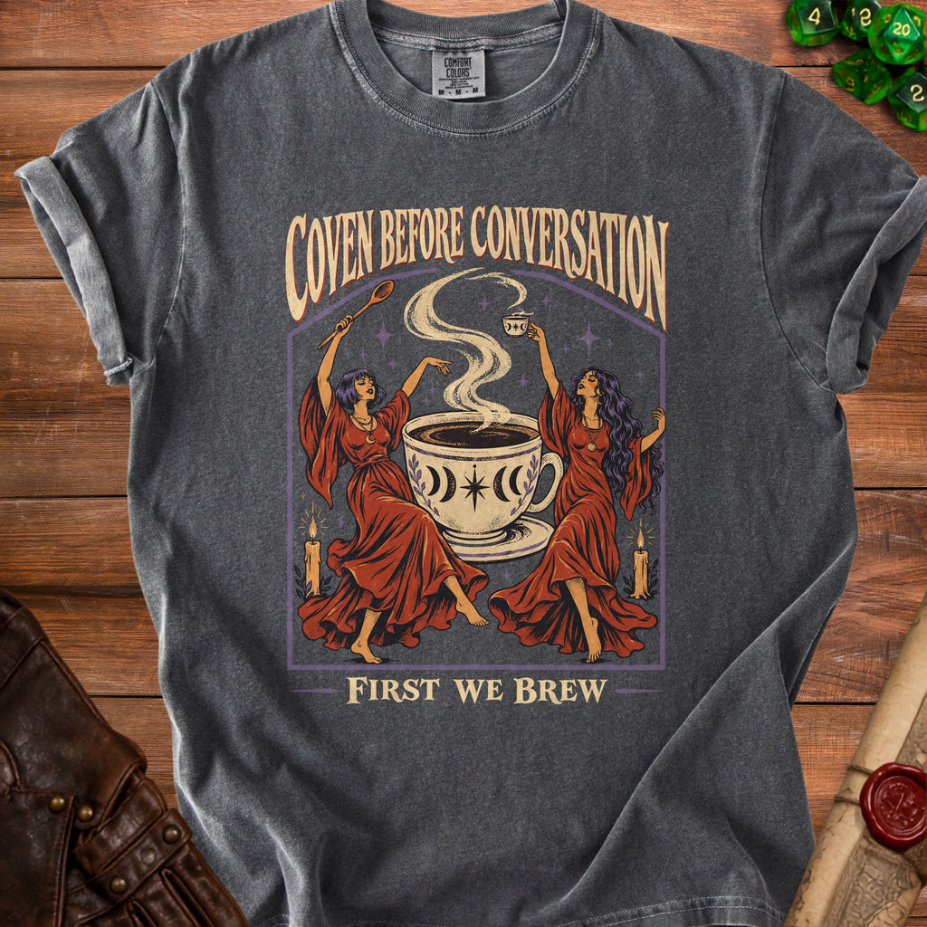 Dark grey t-shirt with "Coven Before Conversation, First We Brew" text and witchy coffee art.