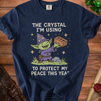 Navy t-shirt with graphic of a smiling goblin wizard holding a brick, text reads "The crystal I'm using to protect my peace this year."