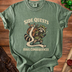 Green t-shirt with raccoon graphic and "SIDE QUESTS HAVE CONSEQUENCES" text.