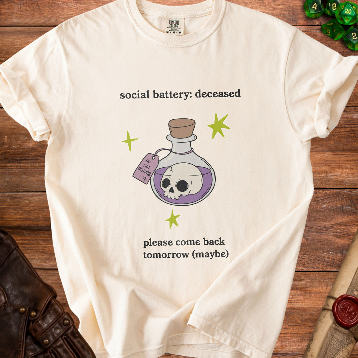 Cream t-shirt with "social battery: deceased" and a skull in a bottle graphic.