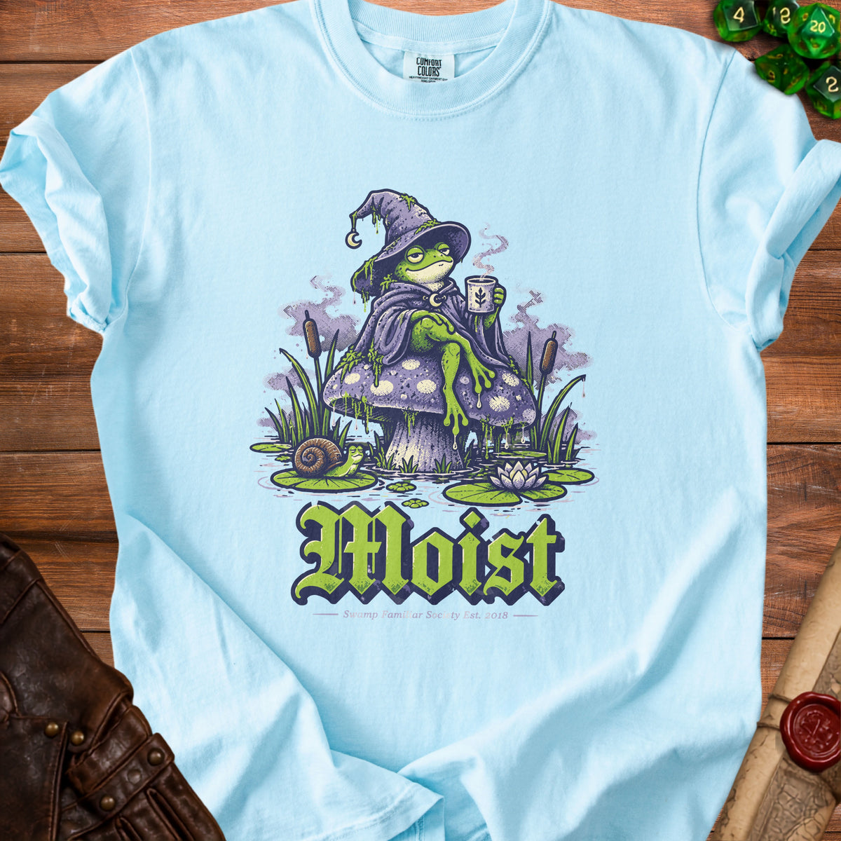 Light blue t-shirt with a frog wizard sitting on a mushroom, text "Moist".