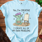 Light blue t-shirt with a goblin artist and text "Yes, I'm CREATIVE I CREATE ALL OF MY OWN PROBLEMS".