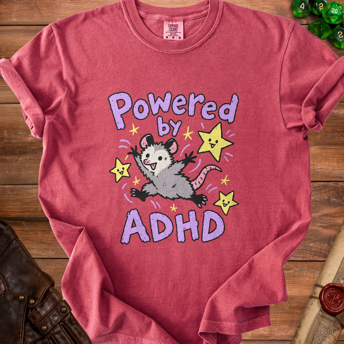 Red t-shirt with a cartoon opossum and stars, reading "Powered by ADHD".