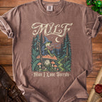 Brown t-shirt with a graphic of a wizard frog reading a book titled "Field Guide" in a forest.