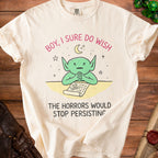 Cream t-shirt with goblin looking at a list titled "horrors" and text.