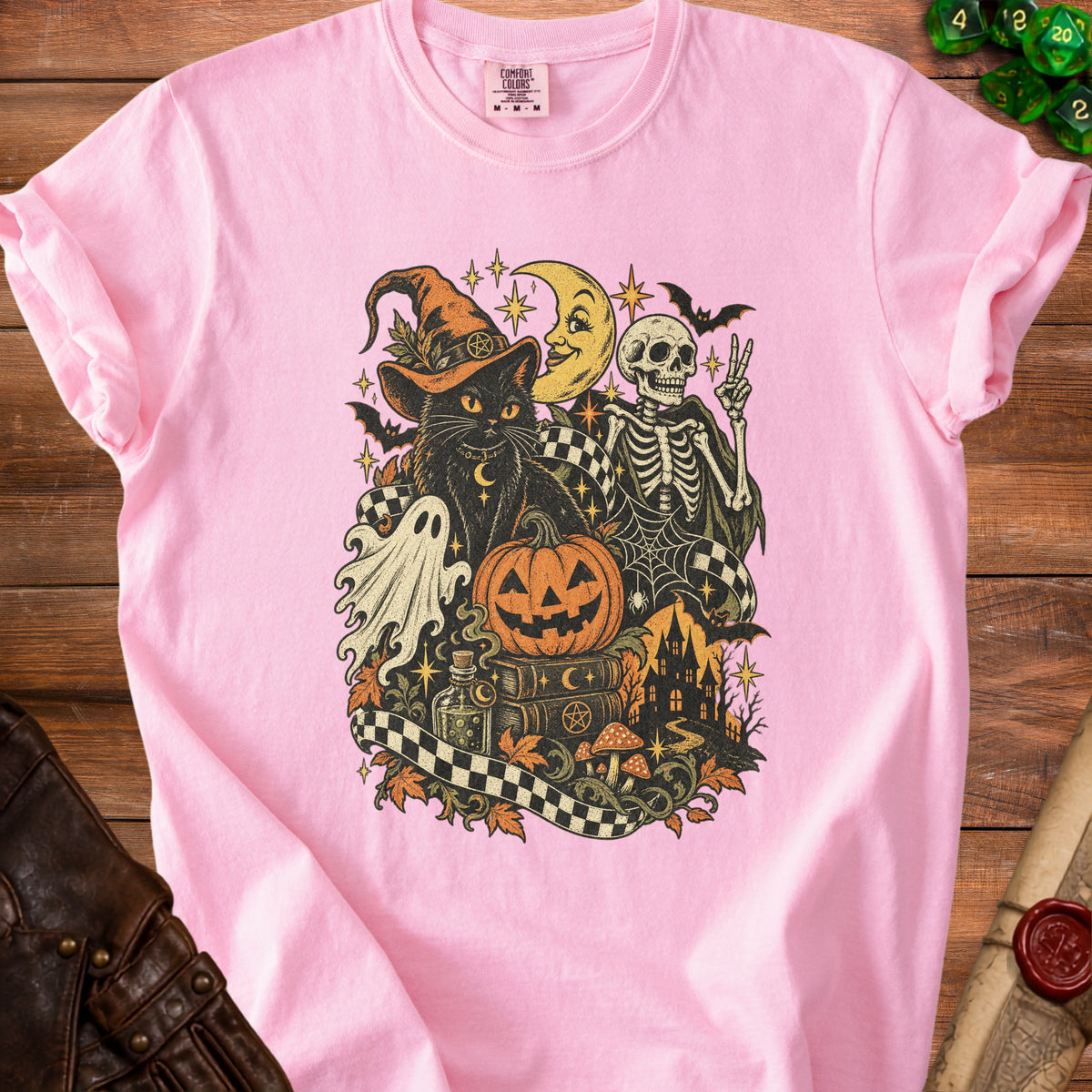 Pink t-shirt with black cat, skeleton, ghost, and Halloween-themed graphic.