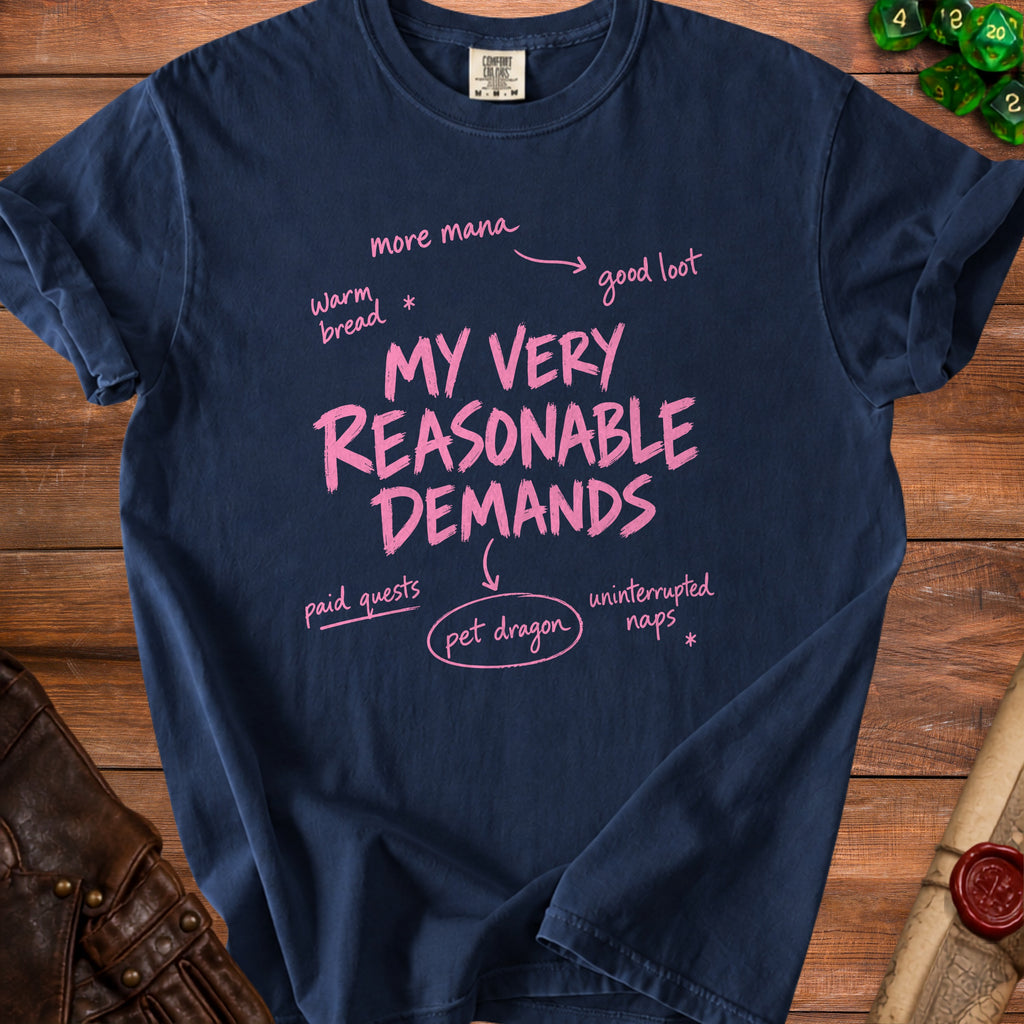 Navy t-shirt with pink text: "My Very Reasonable Demands", "more mana", "warm bread", "good loot", "paid quests", "pet dragon", and "uninterrupted naps".
