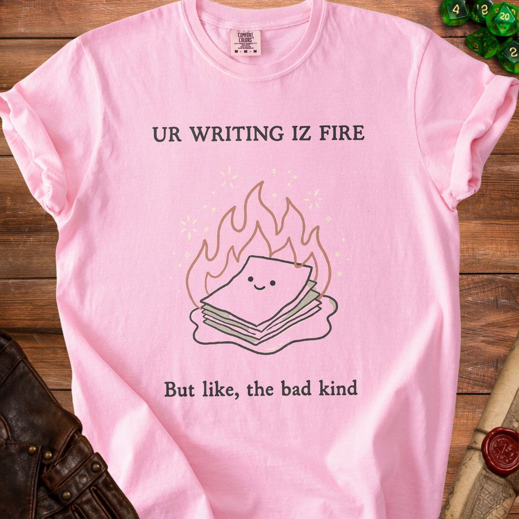 Pink t-shirt with "UR WRITING IZ FIRE But like, the bad kind" text and cartoon.