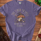 Purple t-shirt with a mushroom wizard graphic reading "Too tired to spell but not too tired to judge."
