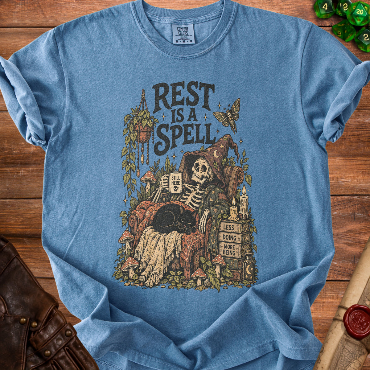 Blue t-shirt with skeleton, cat, and text "Rest Is A Spell".