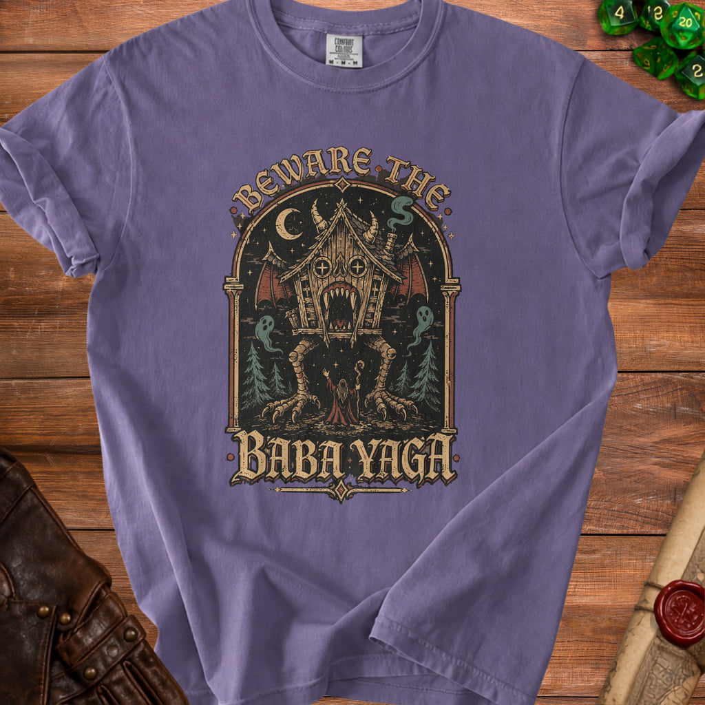 T-shirt graphic with "Beware the Baba Yaga" text, featuring a scary hut on chicken legs.