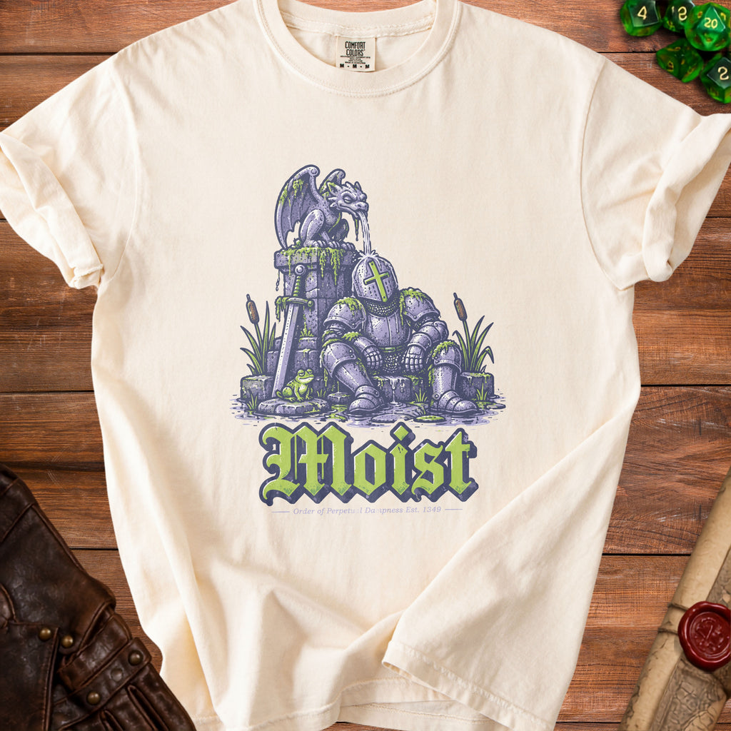 Cream t-shirt with knight receiving water from gargoyle, frog, and "Moist" text.