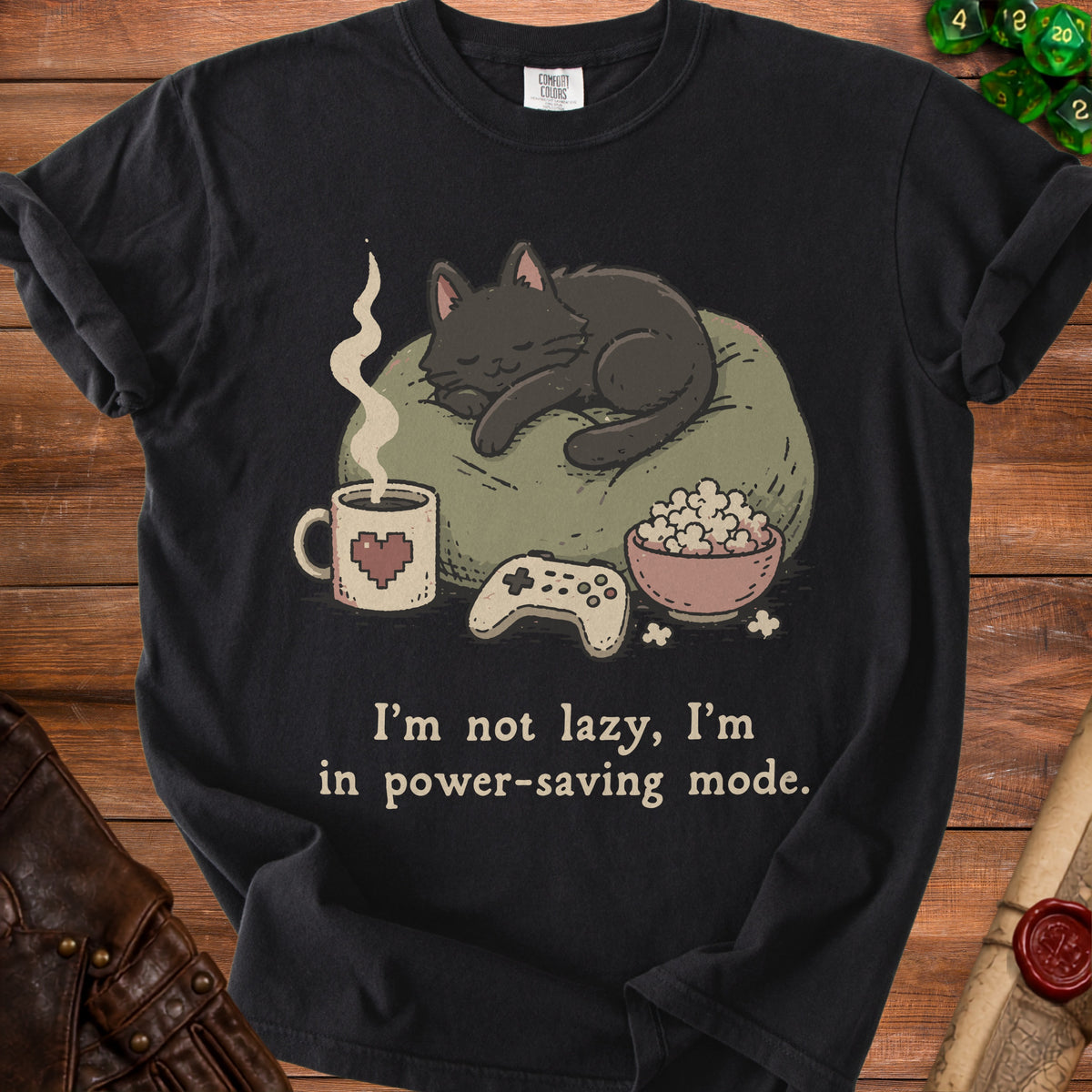 Black t-shirt graphic with sleeping cat, coffee, popcorn, and game controller.
