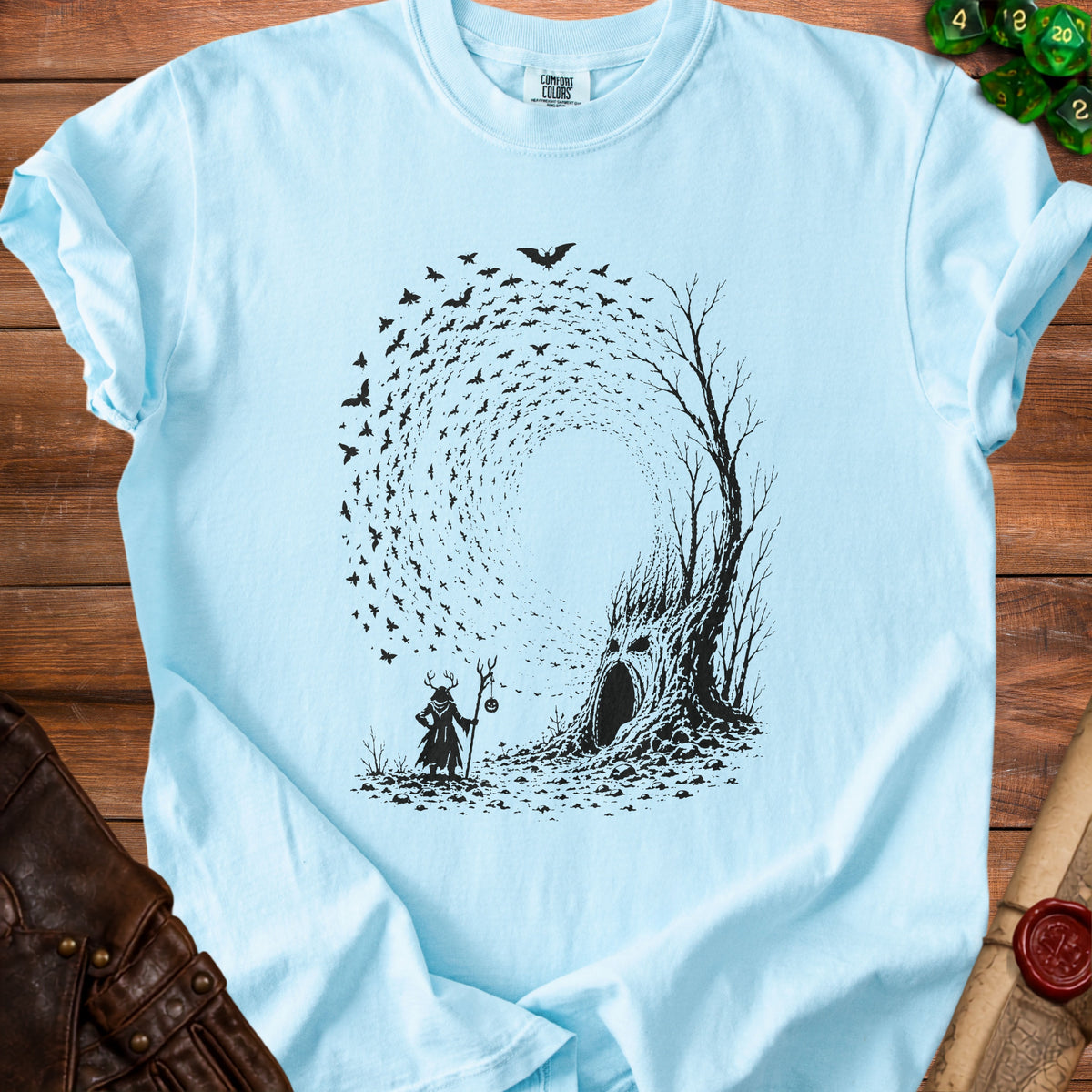 Light blue t-shirt with a black graphic of a cloaked figure, a spooky tree, and swirling bats.