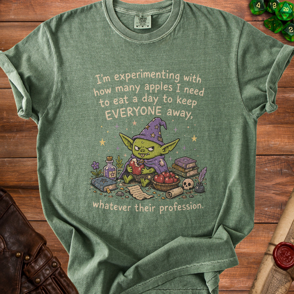 Green t-shirt with illustration of a goblin eating an apple and text about apples.