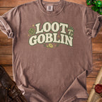 Brown t-shirt with "Loot Goblin" text, dice, mushrooms, and coins graphic.