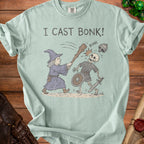 Light blue t-shirt with "I CAST BONK!" graphic of a wizard hitting a skeleton.