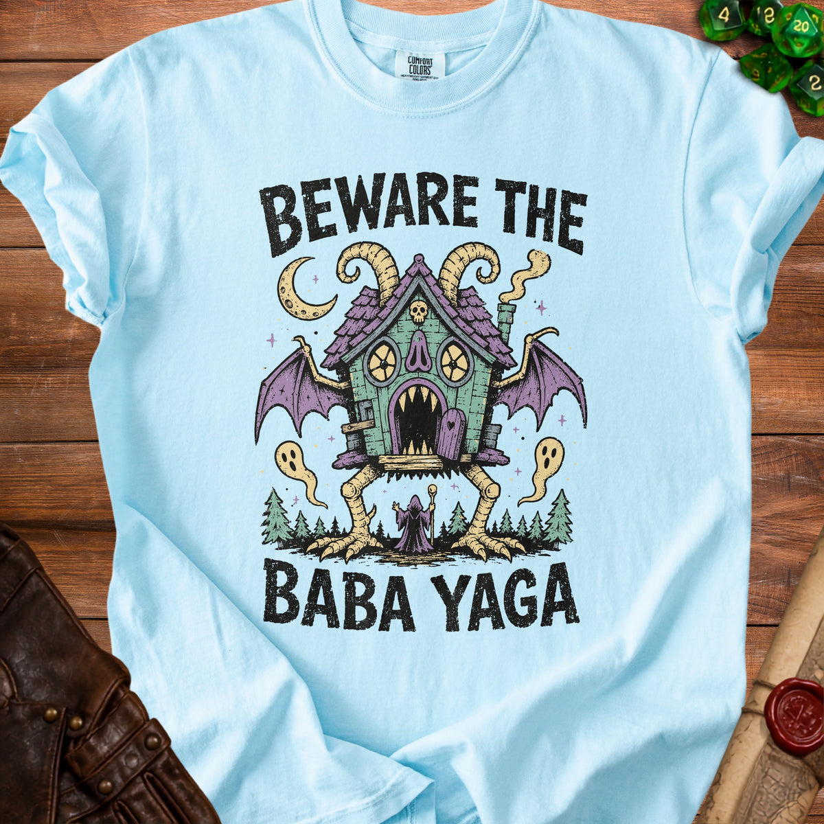 Light blue t-shirt graphic featuring "Beware the Baba Yaga" text and illustration.