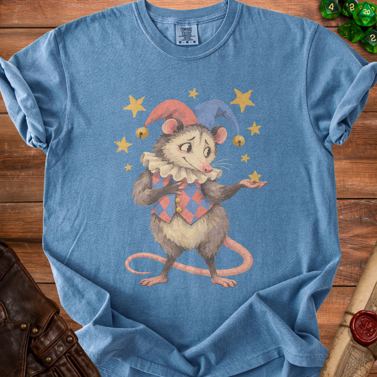 Blue t-shirt with a watercolor illustration of a jester opossum holding a star.