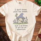 Cream t-shirt with illustration of a mushroom wizard and text about adventure.