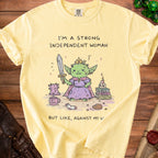 Yellow t-shirt with a graphic of a goblin holding a sword and the text "I'm a strong independent woman, but like, against my w".