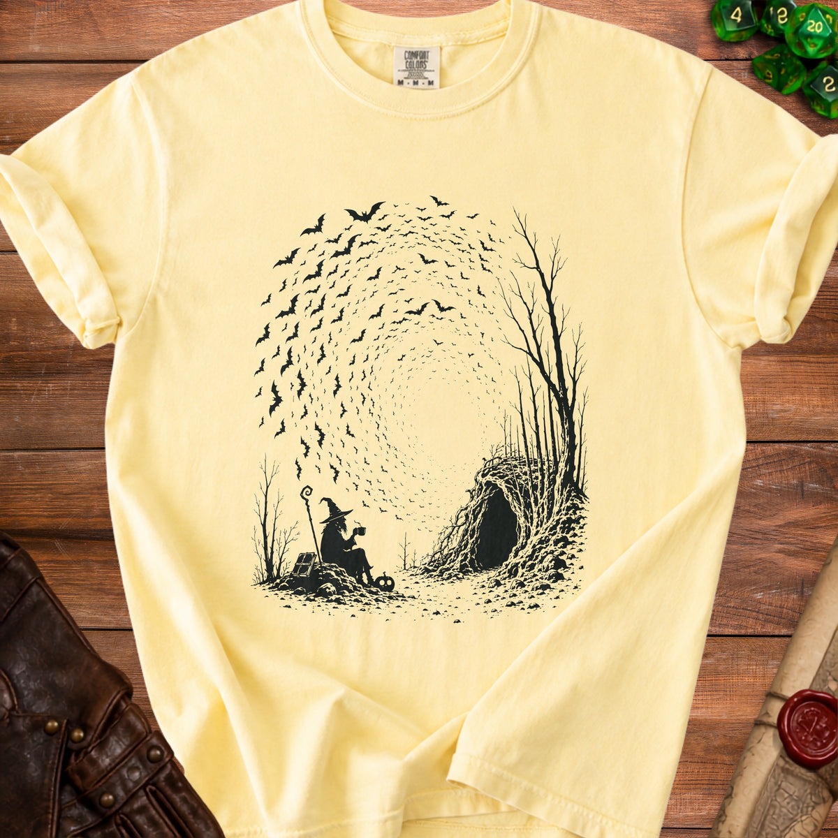 Witch silhouette with a mug, staff, and pumpkin, surrounded by bats and trees near a cave.
