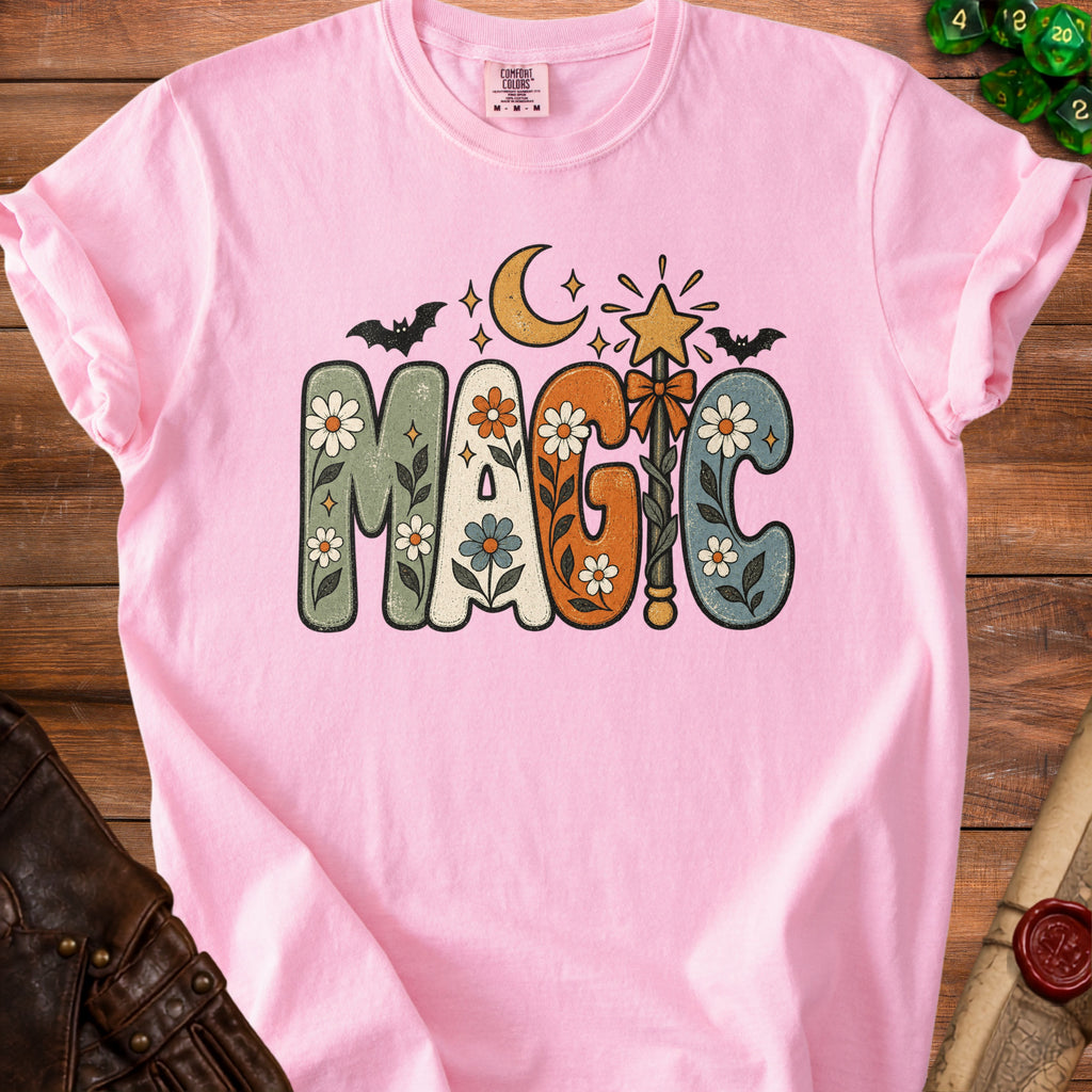 Pink t-shirt with "MAGIC" text in groovy font with floral and celestial designs.