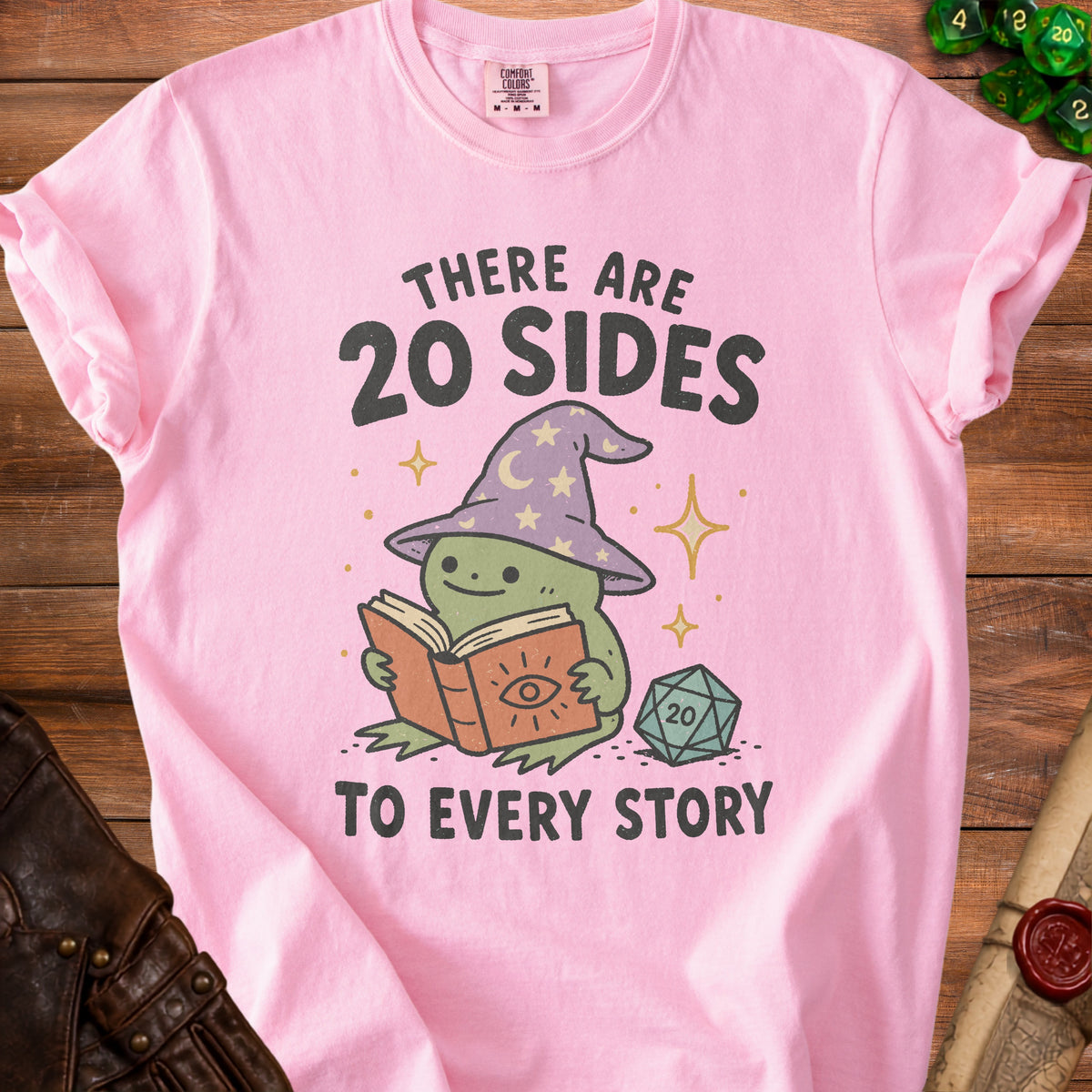 Pink t-shirt with a frog in a wizard hat reading a book and saying "There are 20 sides to every story".