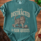 Teal t-shirt with a cat, dice, and text "Easily Distracted By Side Quests".