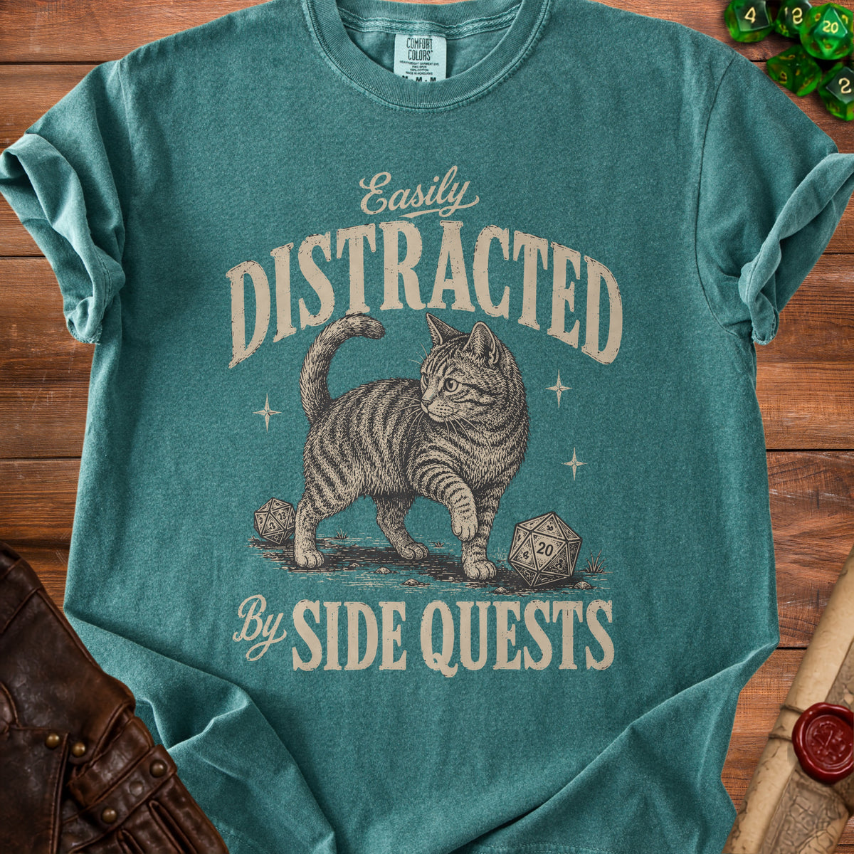 Teal t-shirt with a cat, dice, and text "Easily Distracted By Side Quests".