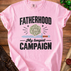 Pink t-shirt with "Fatherhood My Longest Campaign" text and D20 die graphic.