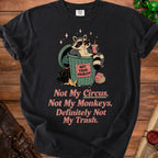Black t-shirt with raccoon in trash can graphic, "Not Your Problem" and "Not My Circus, Not My Monkeys, Definitely Not My Trash." text.