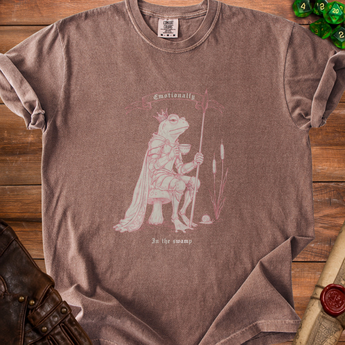 Brown t-shirt with a pink graphic of a crowned frog in armor holding a spear and a cup.