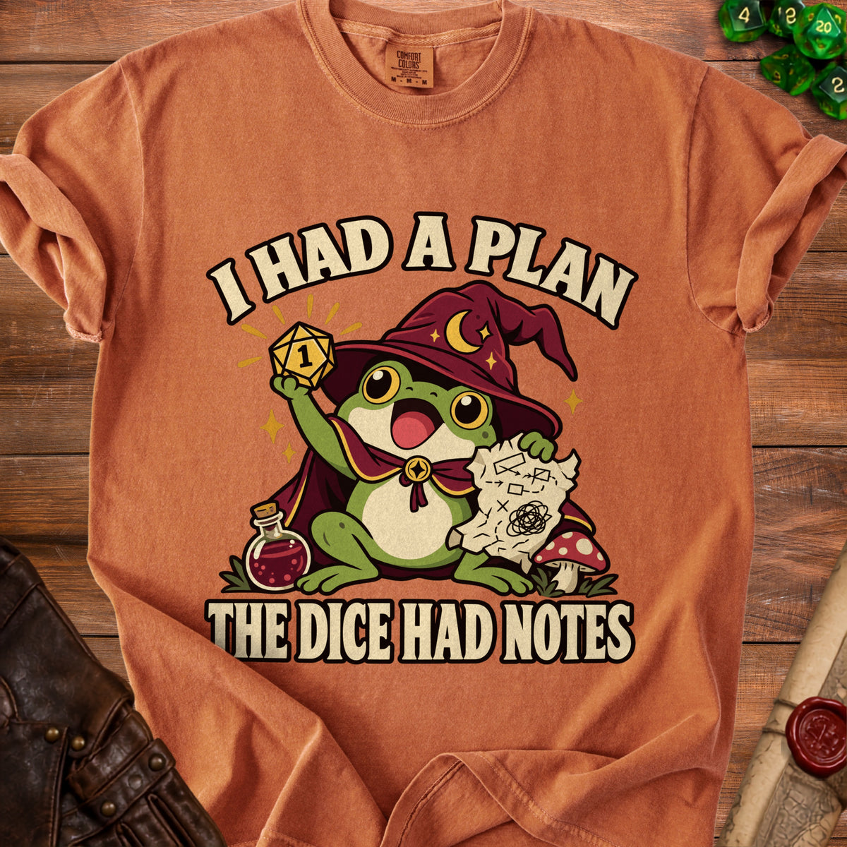 An orange t-shirt featuring a graphic of a wizard frog holding a die and a map.