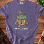 Purple t-shirt with a cartoon wizard frog holding a mug and a wand, text reads "TOADALLY SPENT."