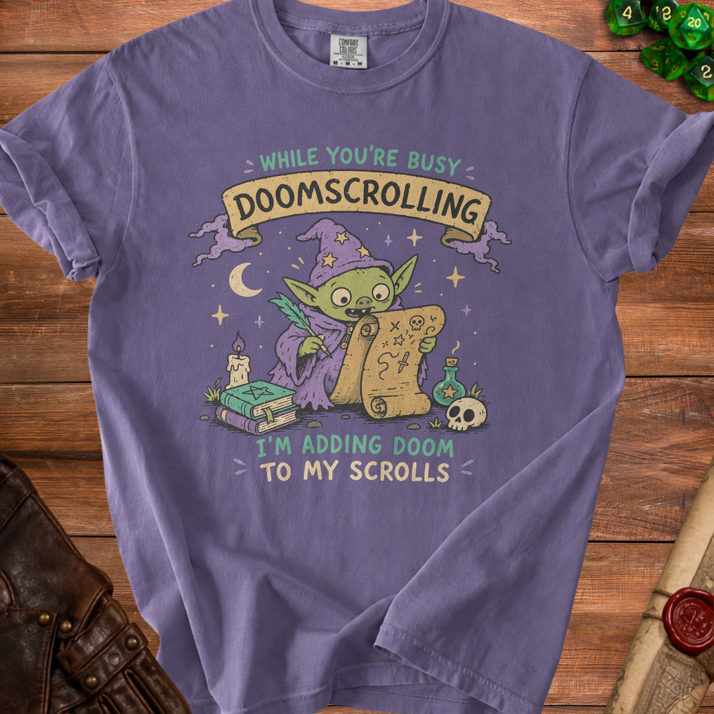 Purple t-shirt with illustration of a goblin wizard reading a scroll, "DOOMSCROLLING" and "I'M ADDING DOOM TO MY SCROLLS".