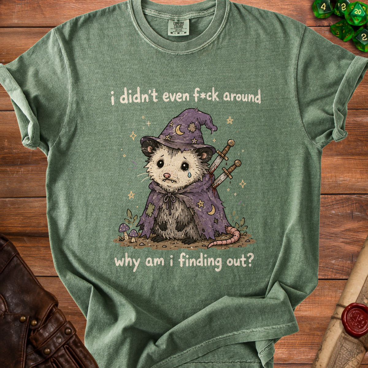 Green t-shirt with a sad possum wearing a wizard hat and text: "i didn't even f*ck around why am i finding out?".