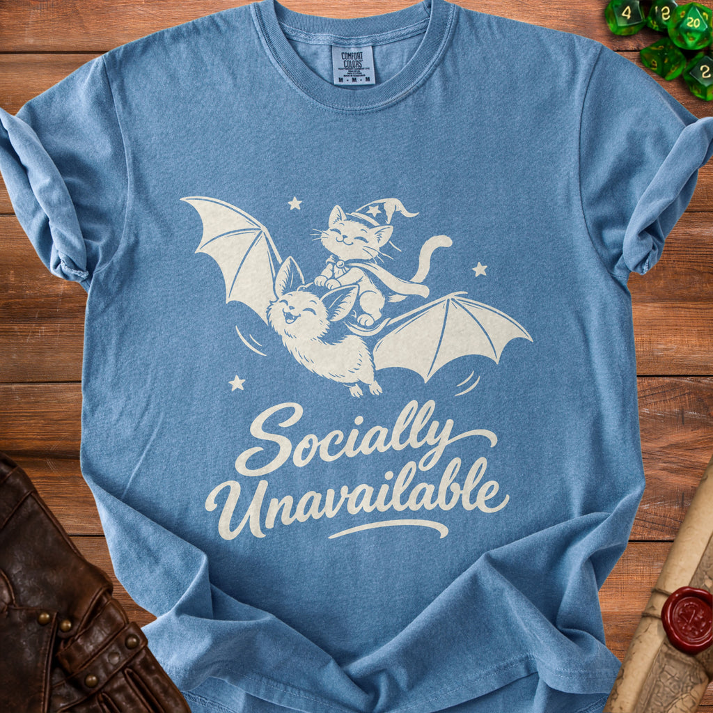Blue t-shirt with white graphic of cat riding bat, "Socially Unavailable" text.