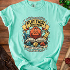 Mint green t-shirt with "Plot Twist Department" and "Expect Complications" graphic.