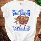 White t-shirt with "Mushroom Foraging Expedition" text and goblin illustration.