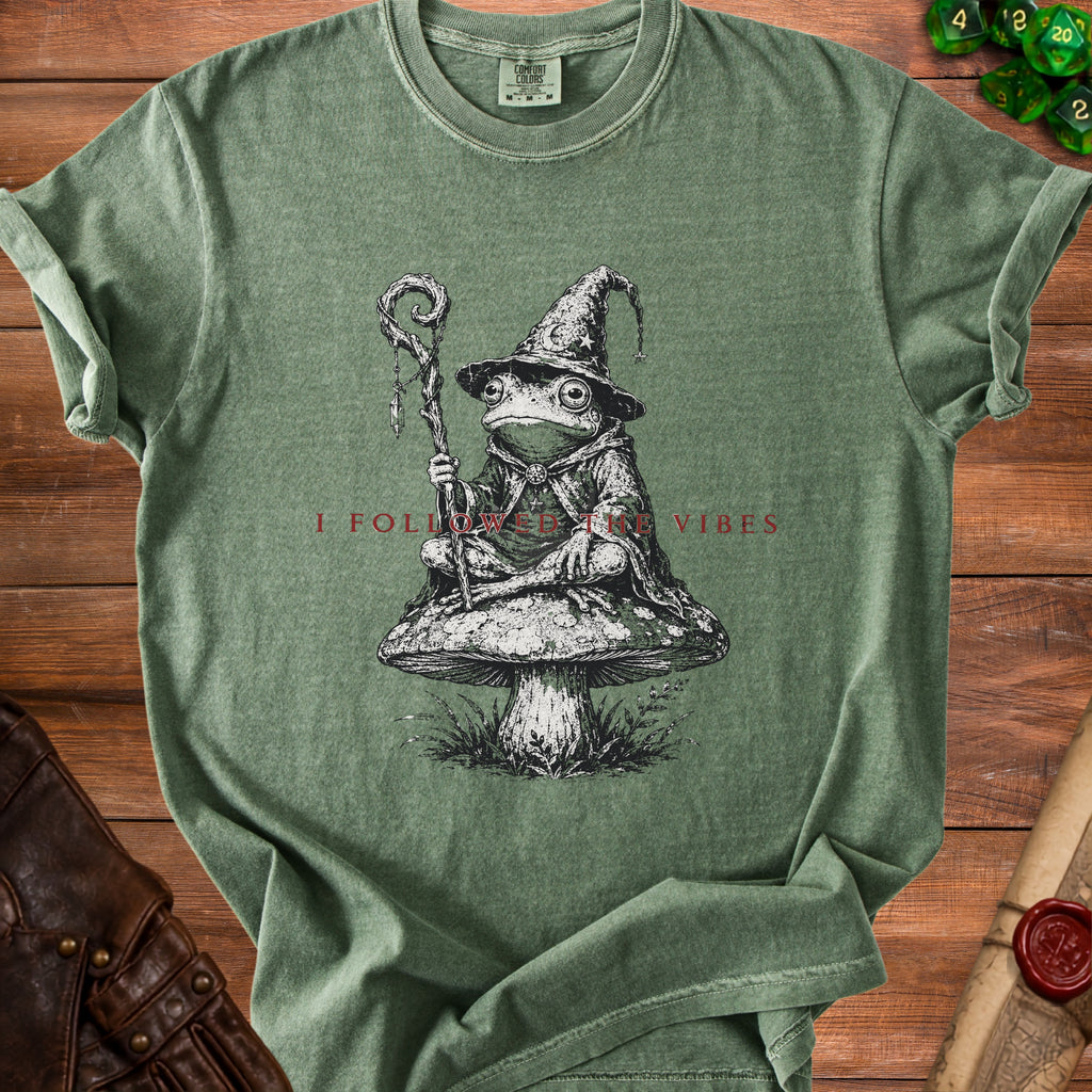 Green t-shirt with a frog wizard on a mushroom and the text "I FOLLOWED THE VIBES".