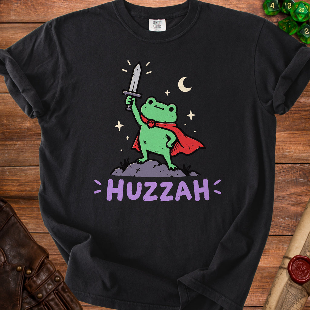 Black t-shirt with a cartoon frog in a red cape holding a sword, text "HUZZAH".